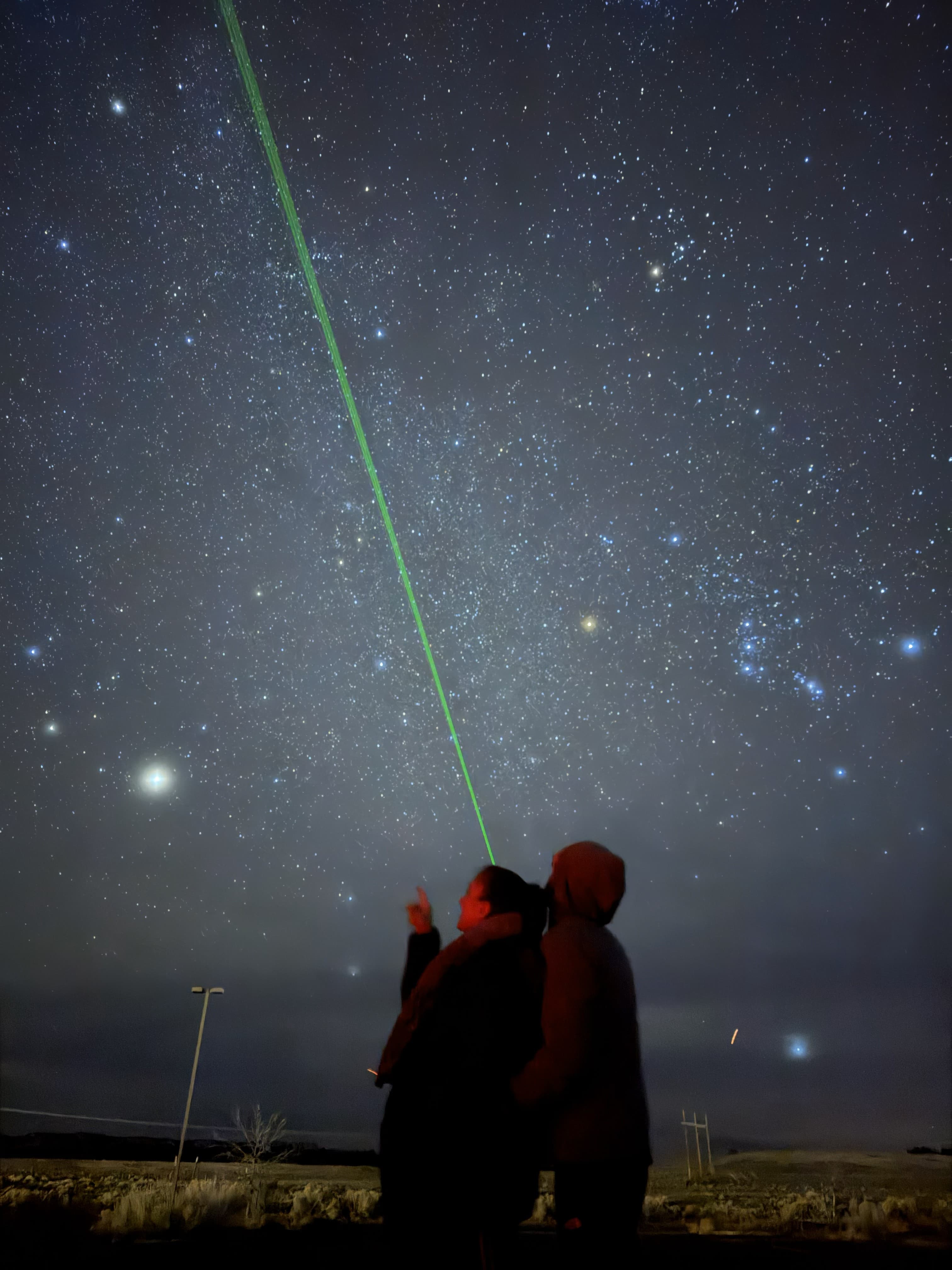 Two guests under a starry sky following a green laser pointer
