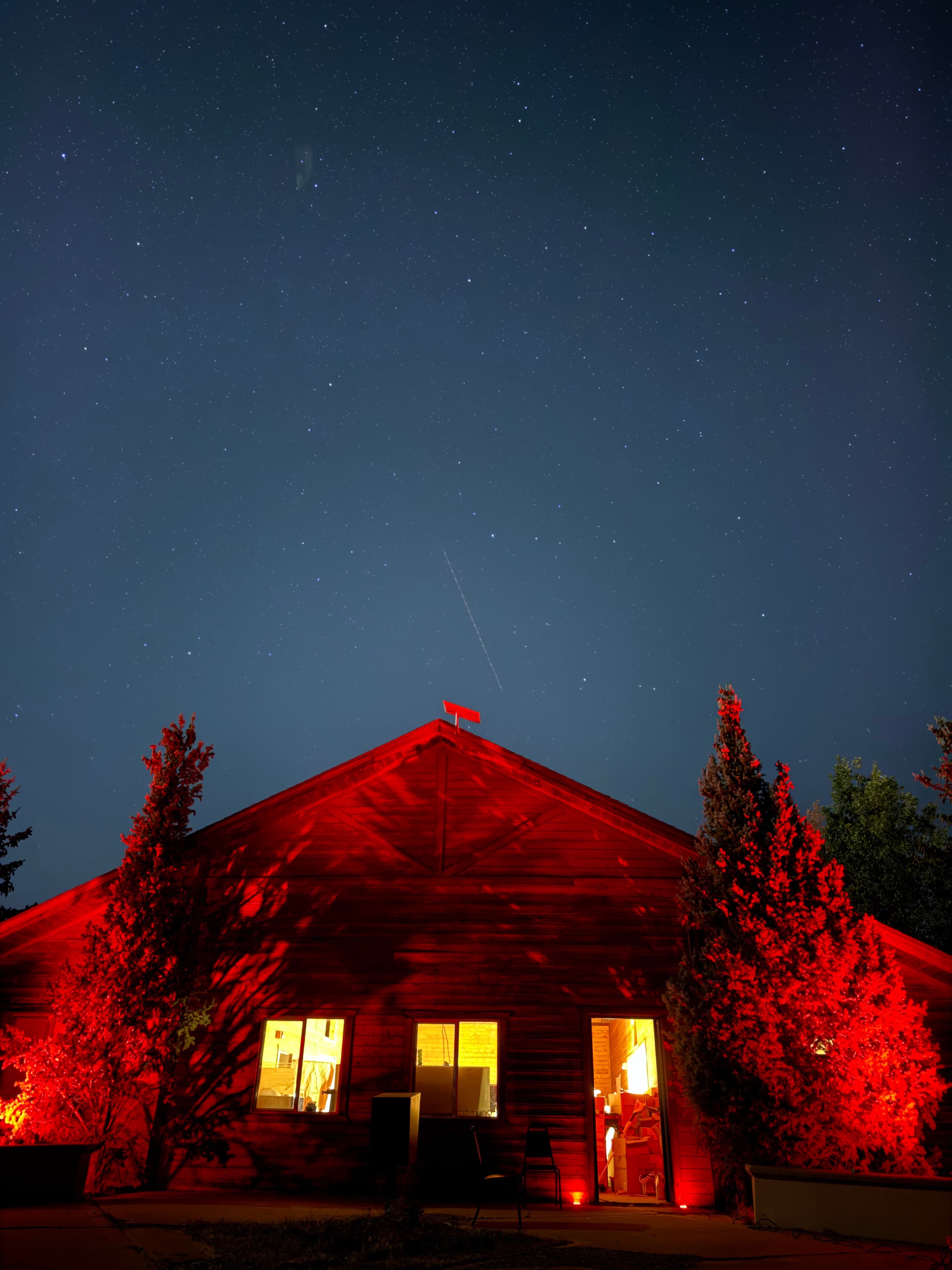A wooden cabin glowing red under a starry night sky