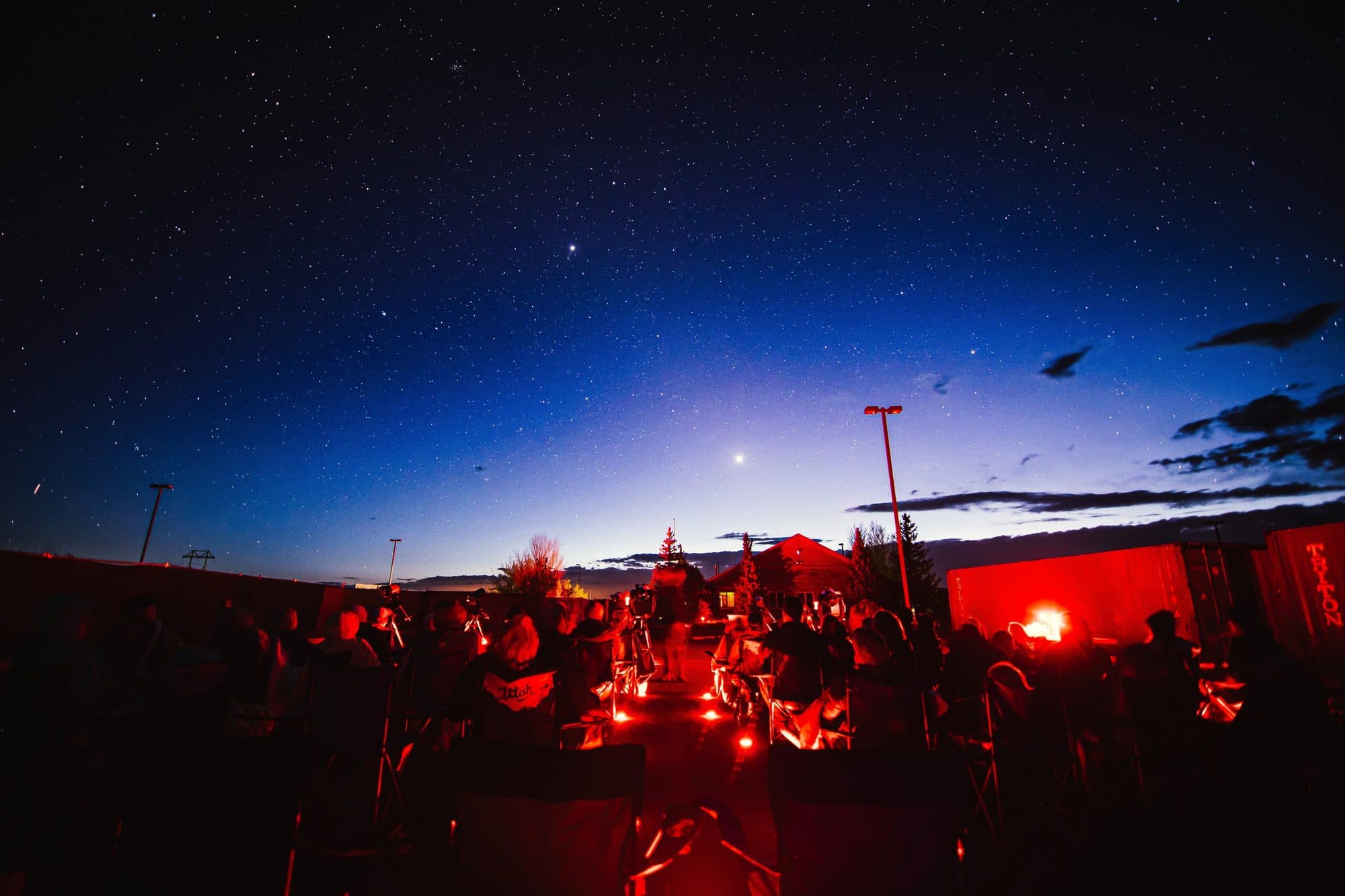 A wide view of the whole group seated under the stars at blue hour
