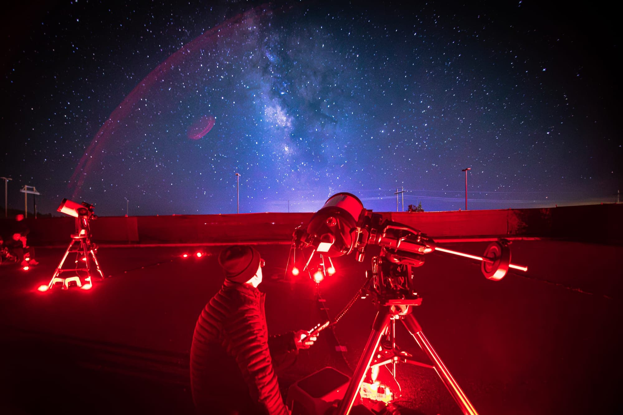 A guide setting up a tracking mount as the Milky Way arch rises over the field