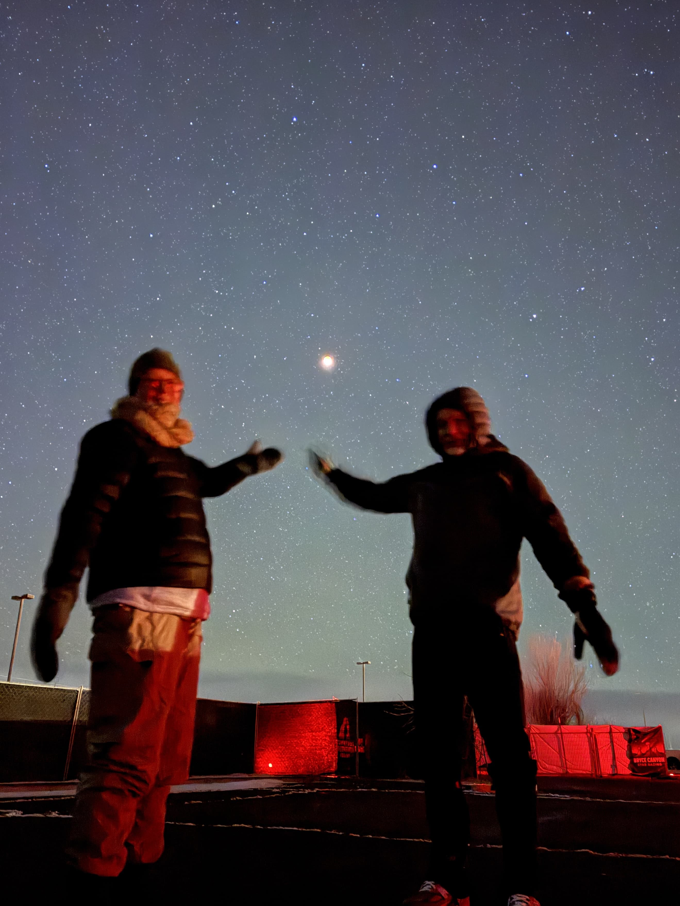 Two guests pointing at a bright object in the night sky
