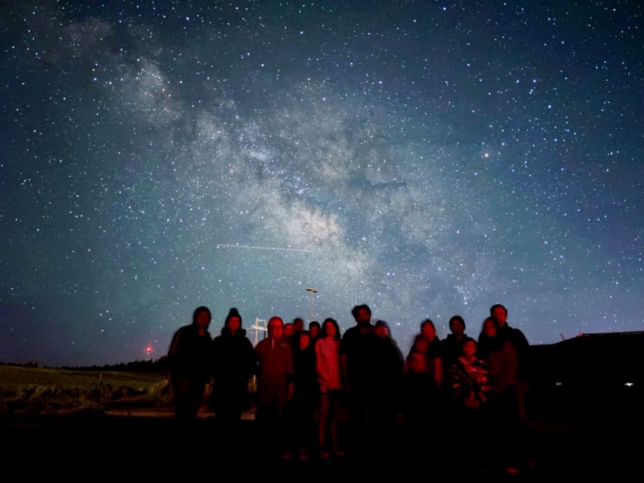 A tour group gathered for a portrait beneath the core of the Milky Way