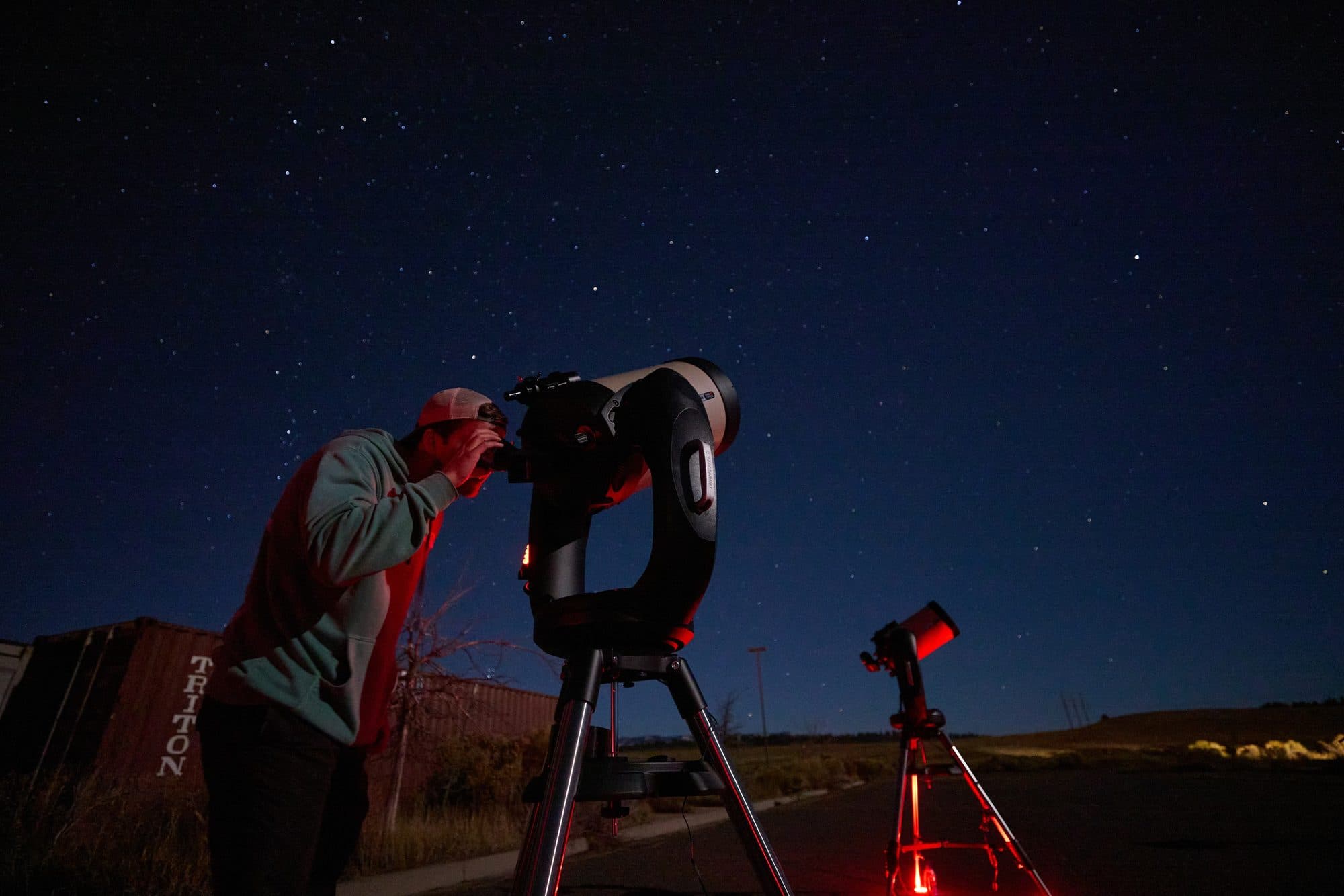 A guest leaning into the eyepiece of a telescope under a darkening sky