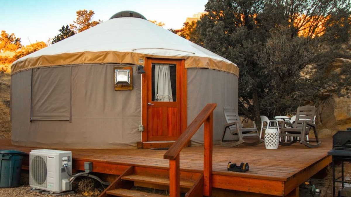 A canvas yurt on a wooden deck at Escalante Yurts, sunset light on the cliffs behind